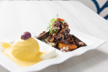 Black peel eviction, accompanied by huancaína potatoes, on a white plate.
