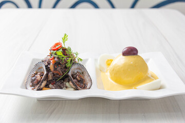 Black peel eviction, accompanied by huancaína potatoes, on a white plate.
