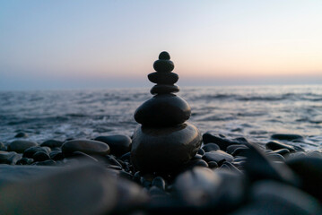 pyramid of pebble stones on the background of the sea in the sunset light