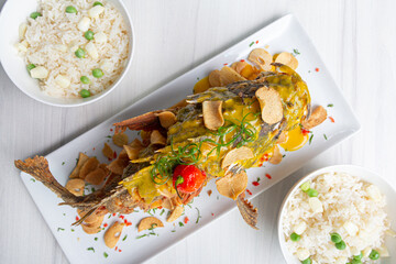 Crispy dorado fish, accompanied by fried yuccas with sauce.
