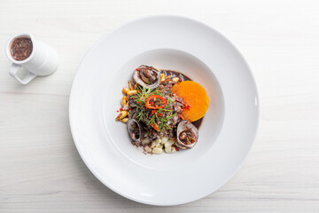 Black ceviche with shell, very typical in Peru. on white plate.
