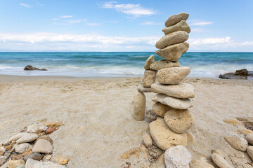 Fototapeta na wymiar Zen stones stack balanced on beach with sea and clear blue sky in background