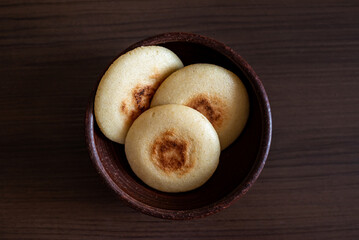 Venezuelan arepas on a bowl on a dark brown wooden background
