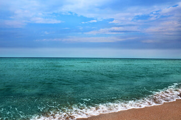 Blue sea wave on a pebble beach.