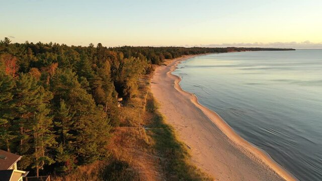 Aerial view of beachfront houses. Establishing shot of waterfront homes. Sunset sunrise sunlight,  Fall Autumn colorful trees. Midwest USA, Door county Wisconsin, lake Michigan.