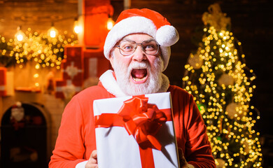 Surprised Santa Claus with Christmas gift. Bearded Man in santa costume with big present box. Merry Christmas. Happy New year.