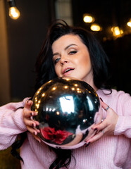 Naklejka premium Beautiful attractive female with christmas ball. Pretty woman in sweater posing with christmas ball.