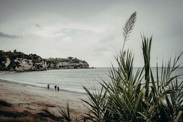 Panoramablick - Drei Kinder am Strand von Tropea an einem bewölkten Tag (Kalabrien, Italien)