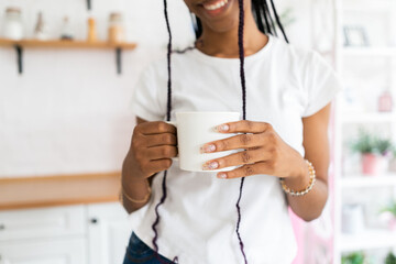 White mug in the hands of black young woman with long beautiful nails