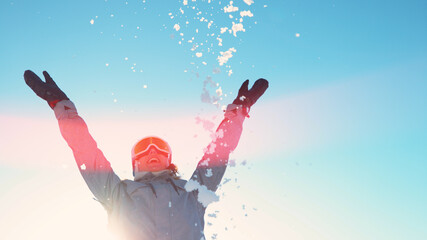 COPY SPACE: Cheerful young woman throws a handful of snow on a sunny winter day.