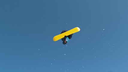 Spectacular shot of a male snowboarder jumping off kicker and doing a trick.