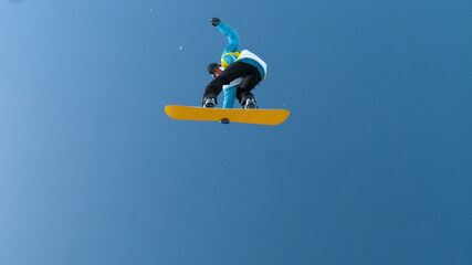 Spectacular shot of young snowboarder jumping high in the air and doing a trick
