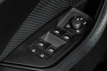 Close up view of button controlling window in modern car interior. Vehicle interior detail. Door handle with windows controls