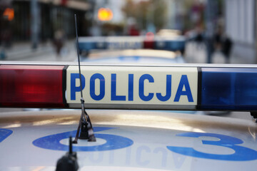 Sygnalizator błyskowy niebieski na dachu radiowozu policji polskiej w nocy.
