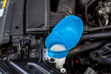 Windshield washer fluid reservoir cap. Windshield washer liquid cap inside a car engine. Closeup cap windshield cleaner water liquid tank.