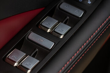 Obraz premium Close up view of button controlling window in modern car interior. Vehicle interior detail. Door handle with windows controls