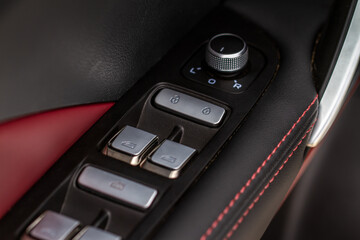 Obraz premium Close up view of button controlling window in modern car interior. Vehicle interior detail. Door handle with windows controls