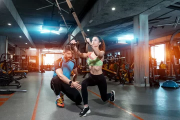 Rollo young female exercising and has workout with trx and personal trainer in gym © goami