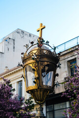 Fototapeta na wymiar Beautiful golden streetl lampost with crucifix cross on top on in front of Agia Paraskevi Church on the pedestrian part of Aiolou street