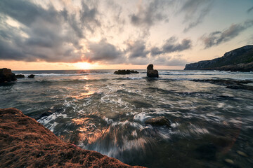 Sunrise at the touristic beach Las Rotas in Denia,  Spain in a cloudy day. There are strong tides and waves. It's a very visited beach at the marine reserve of San Antonio Cape in Alicante