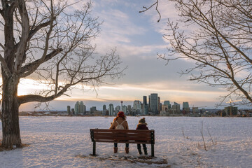 Mother and son sitting on a bench in a snowy field in Calgary, Alberta