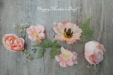 Peach Colored Silk Flowers with Greenery on Light Wooden Panel with Happy Mother's Day Greeting