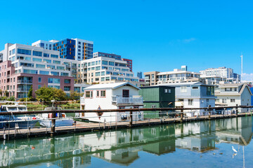 Houseboats on shallow water of Mission Creek Channel. Residential mid-rise and high-rise apartment...