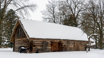 Beautiful winter nature background. Rural landscape with an old barn. Thatched roof barn covered in snow in winter.