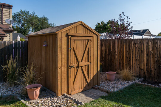 A backyard tool shed with a wooden fence.