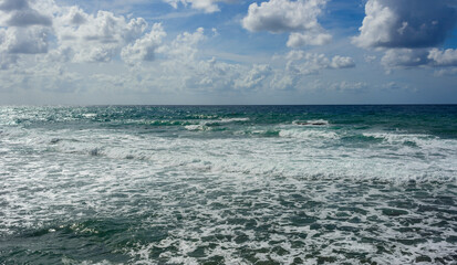 landscape of stormy Mediterranean sea with blue sky and white clouds and white sea foam off the coast of Turkey, Avsalar, Alanya during a storm in autumn