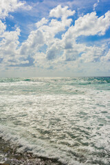 Obraz premium landscape of stormy Mediterranean sea with blue sky and white clouds and white sea foam off the coast of Turkey, Avsalar, Alanya during a storm in autumn