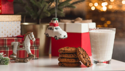 Merry Christmas 2022. Beautiful background with chocolate chip cookies and a glass of milk for Santa Claus. Celebrating the winter New Year holidays. The concept of the beginning of the year.