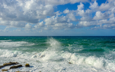 landscape of stormy Mediterranean sea with blue sky and white clouds and white sea foam off the coast of Turkey, Avsalar, Alanya during a storm in autumn