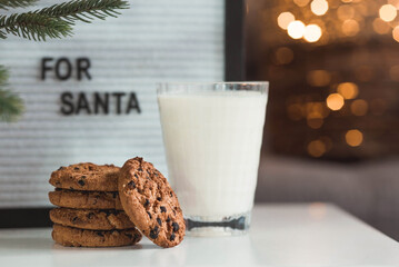Merry Christmas 2022. Beautiful background with chocolate chip cookies and a glass of milk for Santa Claus. Celebrating the winter New Year holidays. The concept of the beginning of the year.