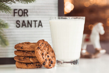 Merry Christmas 2022. Beautiful background with chocolate chip cookies and a glass of milk for Santa Claus. Celebrating the winter New Year holidays. The concept of the beginning of the year.