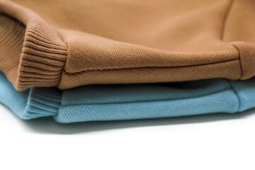 Fototapeta na wymiar Two sweatshirts of blue and ochre color close-up, turned to us with a shoulder seam. Concept: atelier, clothing store brand, cutting and sewing courses, sewing hobby.