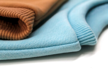 Two sweatshirts of blue and ochre color are close-up.