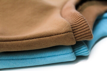 Fototapeta na wymiar Two sweatshirts of blue and ochre color close-up.
