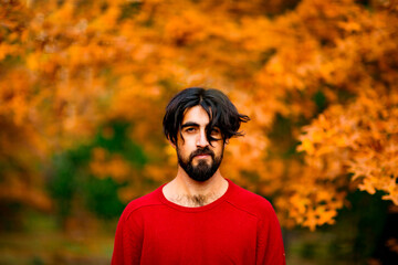 a young man, dark-haired, wearing a hat with a beard, walking in the park, on an autumn day