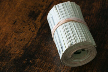 dollars bills rolled, copy space on vintage tone wooden table.