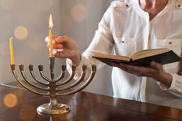 Woman lighting the shamash on Menorah on first day / night of  Chanukah
