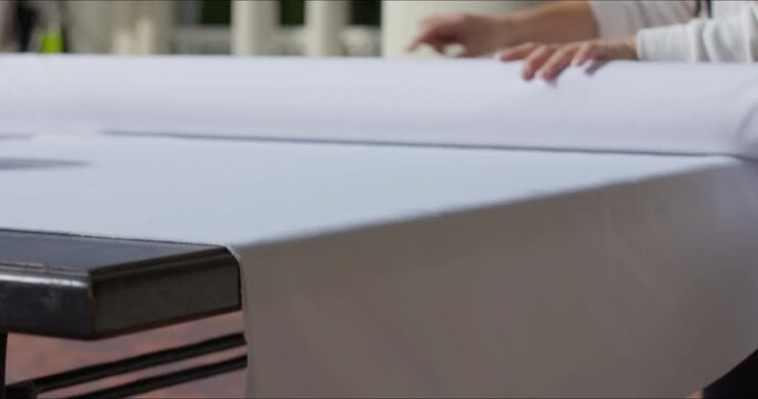 Medium shot of unrecognizable woman laying beautiful tablecloth on dining table