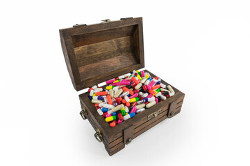 Old wood toy treasure chest overflowing with pills and capsules.