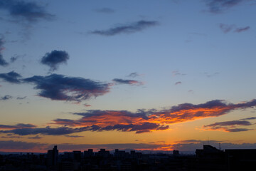 Fototapeta premium 都市の夜明け、早朝ビルの隙間から太陽が昇り辺りはオレンジ色に染まる。ビルはシルエットに浮かぶ