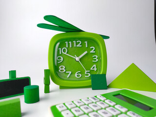 A green alarm clock and calculator with colored wooden cube and puzzle on a white background.