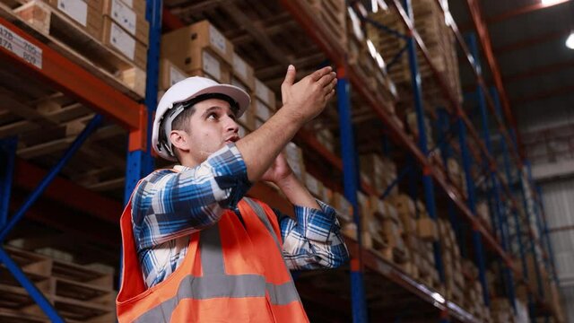 Male staff or worker having call talking on mobile phone call working at depot or distribution center store, slow motion
