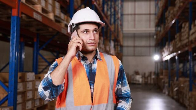 Male staff or worker having call talking on mobile phone call working at depot or distribution center store