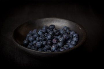 plate of fresh blueberries on dark background