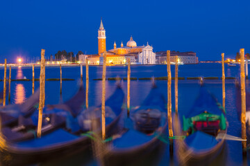 Long exposure shot of Church of San Giorgio Maggiore behind gondolas in Venice, Italy