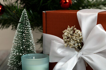 A beautiful present box with white ribbon underneath a Christmas tree.  Christmas decoration.